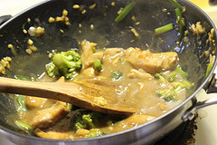 Chicken cooking in garlic sauce in wok with wooden spoon