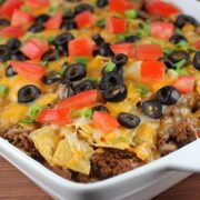 Mexican casserole topped with melted cheese, olives, tomatoes, and green onions