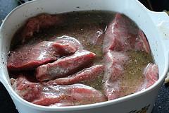 Raw steak marinating in a bowl of marinade