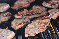 Steak slices being grilled over an open flame