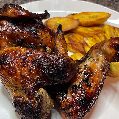 Close up view of jerk chicken on plate with plantains.