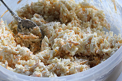Bowl of hashbrowns and cheese mixture being stirred with a spoon