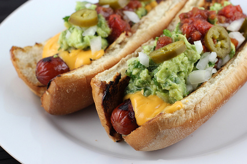 Nacho dogs topped with cheese guacamole and jalapeños