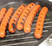 Grilled hot dogs with char marks on the grill