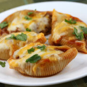 Cheesy taco stuffed pasta shells with seasoned beef and salsa in a baking dish