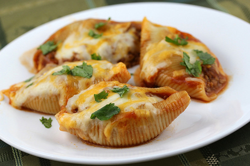 Cheesy taco stuffed pasta shells with seasoned beef and salsa in a baking dish