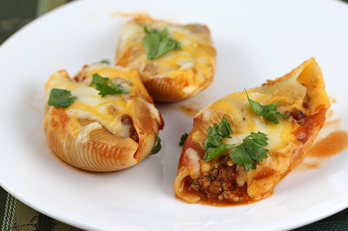 Cheesy taco stuffed pasta shells with seasoned beef and salsa in a baking dish
