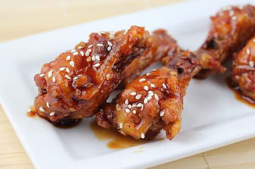 Teriyaki glazed chicken wings served on a white rectangular plate.