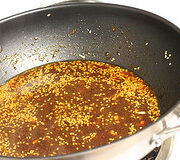 Teriyaki sauce simmering in a pan with garlic and seasonings.