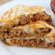 Beef quesadilla slices served with salsa in a white plate