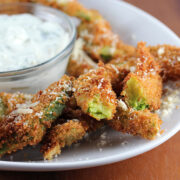 Crispy avocado fries served with ranch dipping sauce on a white plate