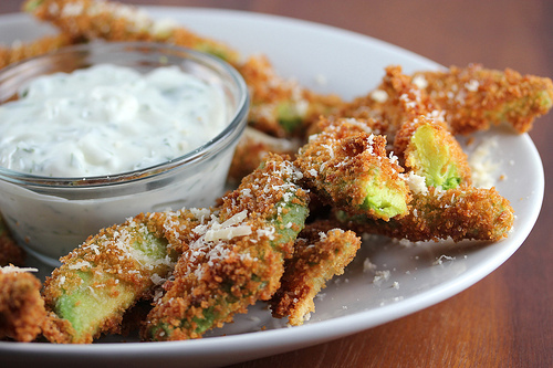Crispy avocado fries served with ranch dipping sauce on a white plate