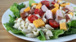 Close up of prepared club pasta salad on white plate.