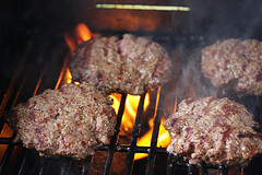 Patties cooking on a grill with open flames