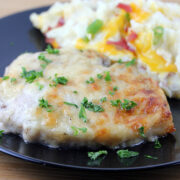 Baked Caesar pork chop garnished with parsley served with cheesy mashed potatoes