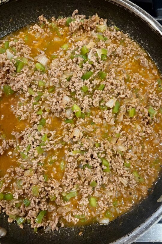 Ground beef, onions, and peppers in a saucepan