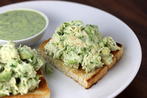 Toast topped with avocado chicken salad and a small bowl of extra dressing on the side