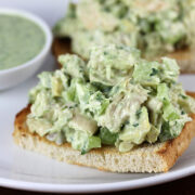Toast topped with avocado chicken salad and a small bowl of extra dressing on the side