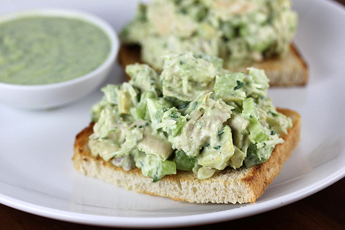 Toast topped with avocado chicken salad and a small bowl of extra dressing on the side