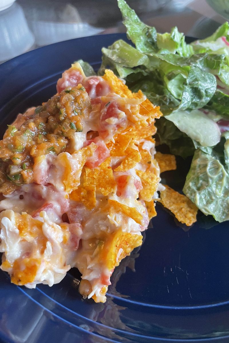 Dorito chicken casserole topped with salsa and served with salad.