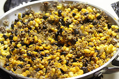Skillet of seasoned ground beef mixed with corn for taco tater tot bake