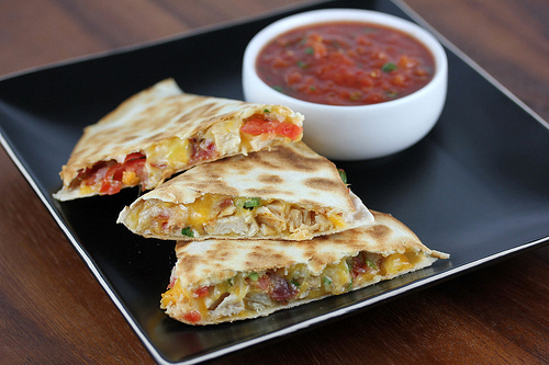 Chicken quesadilla wedges filled with cheese, bacon, and pico de gallo served with salsa