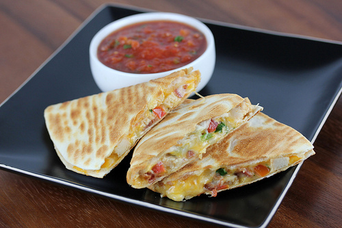 Chicken quesadilla wedges filled with cheese, bacon, and pico de gallo served with salsa
