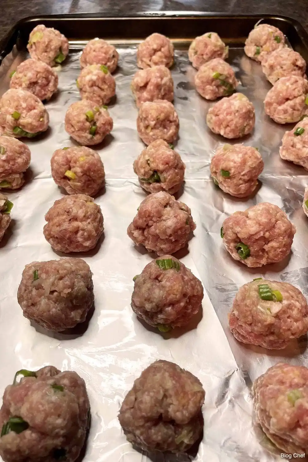 Rolled Hoisin meatballs on baking sheet before cooking. 