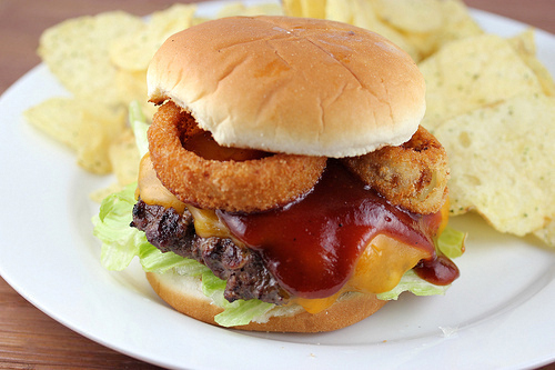 Image of fully assembled Rodeo Burger with onion rings and barbecue sauce on toasted bun