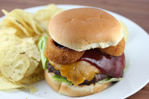 Image of fully assembled Rodeo Burger with onion rings and barbecue sauce on toasted bun