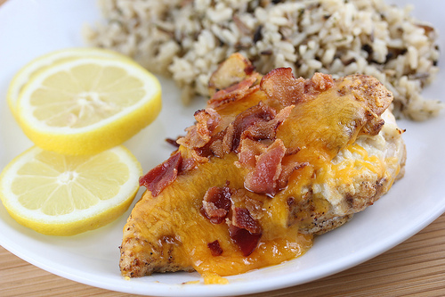 Plate with baked chicken breast served with lemon slices and rice