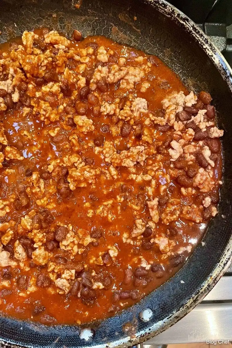 Overhead view of meat and beans cooking in spices for a chopped taco salad.