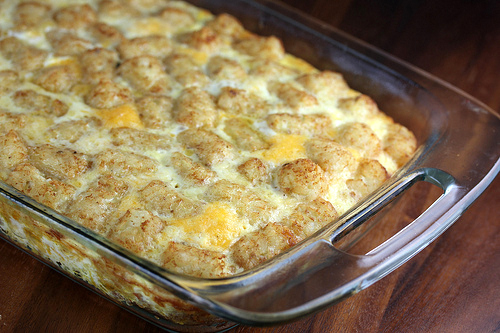 Baked tater tot breakfast casserole topped with melted cheese in a glass dish