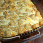 Baked tater tot breakfast casserole topped with melted cheese in a glass dish