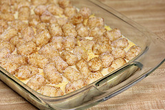 Baked tater tot breakfast casserole topped with melted cheese in a glass dish