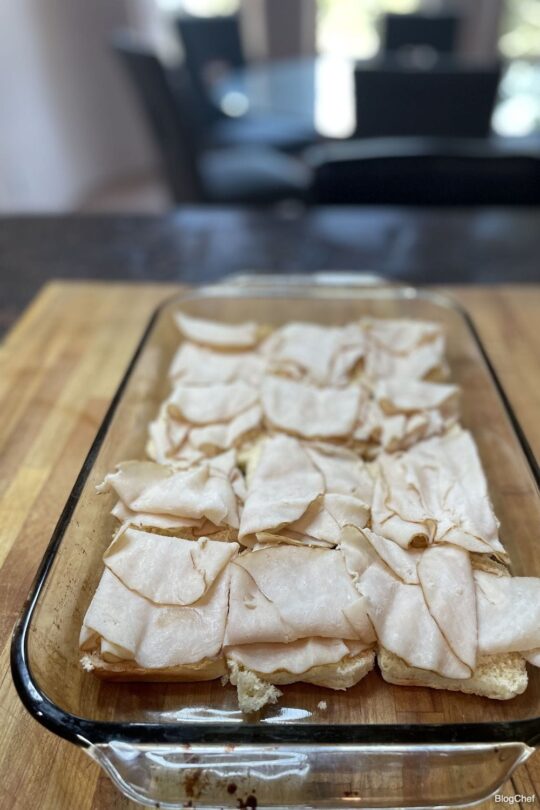 Assembling turkey and cheese sliders with poppy seed sauce.