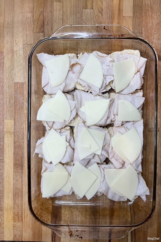 Assembling turkey and cheese sliders with poppy seed sauce.