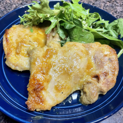 Overhead view of baked chicken thighs recipe, prepared on plate.