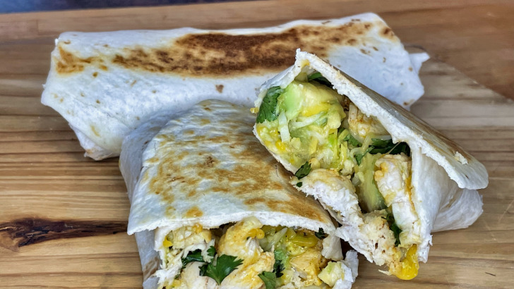 Prepared chicken avocado wraps on cutting board.