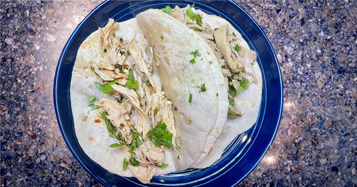 Chicken tacos prepared on plate with soft flour tortillas.