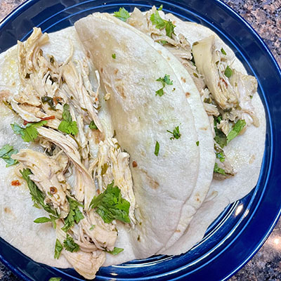 Chicken tacos prepared on plate with soft flour tortillas.