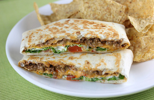 Crunchwrap supreme cut in half showing beef, lettuce, tomato, cheese, and sour cream