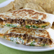 Crunchwrap supreme cut in half showing beef, lettuce, tomato, cheese, and sour cream