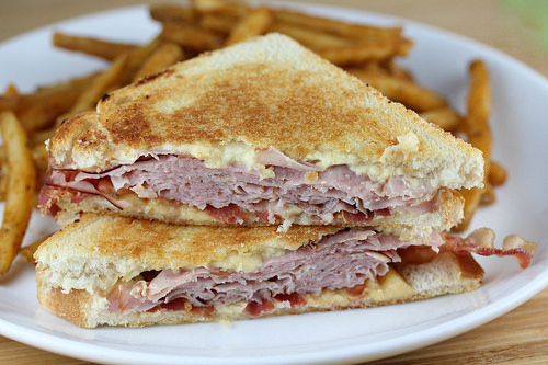 tacked grilled ham and gouda cheese sandwich halves with melted cheese, served with fries
