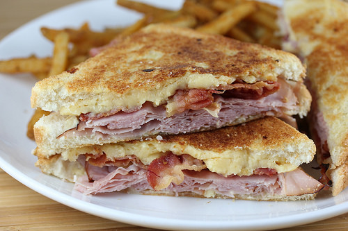 tacked grilled ham and gouda cheese sandwich halves with melted cheese, served with fries