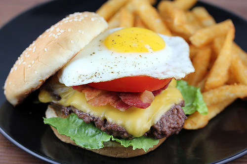 Close-up of Royal Red Robin Burger topped with a fried egg, served with fries