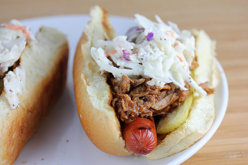 Hot dog with shredded pork, coleslaw, and pickle inside a bun