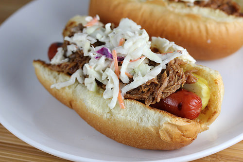Hot dog with shredded pork, coleslaw, and pickle inside a bun