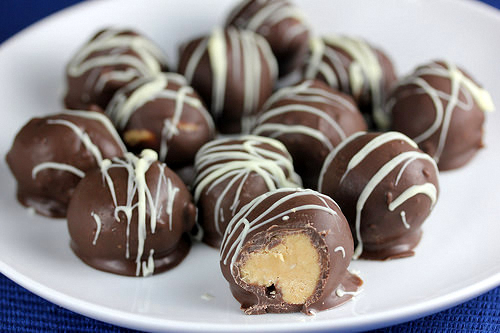 Peanut butter balls coated in chocolate with white drizzle on serving plate