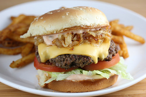 In N Out burger with lettuce tomato cheese and grilled onions served with fries